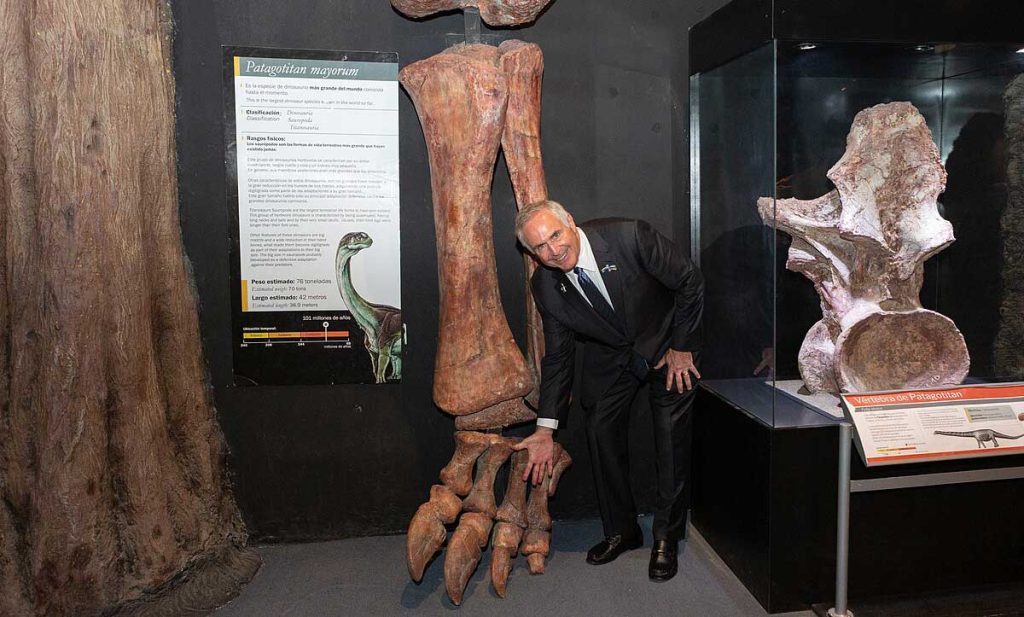 US ambassador to Argentina Marc R. Stanley with Patagotitan bones. The leg fossil is larger than him.