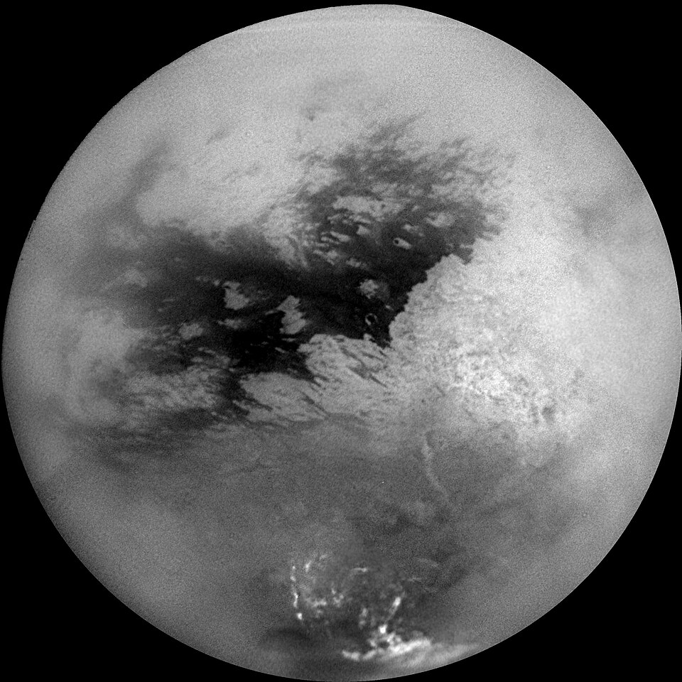 Titan, Saturn’s largest moon, with dark methane lakes visible beneath its hazy atmosphere.