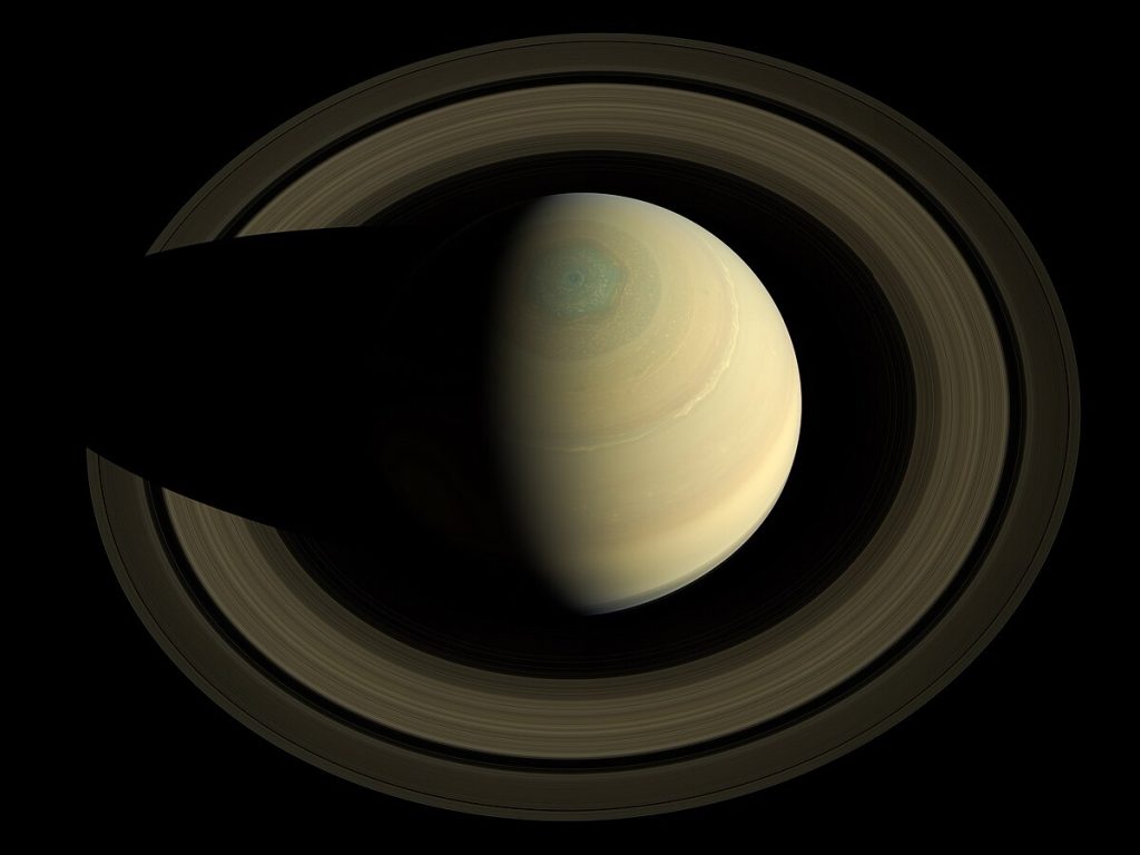 Saturn and its rings viewed from above the north pole, showing the planet's distinctive hexagonal polar vortex and the full ring system encircling it.