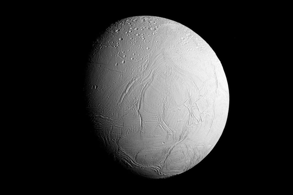 Enceladus, an icy moon of Saturn, showing its bright white surface covered in fractures and ridges, with a heavily cratered northern region.