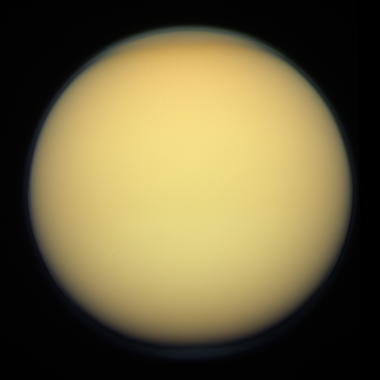 Titan, Saturn's largest moon, showing its thick, hazy orange atmosphere that completely obscures the surface.